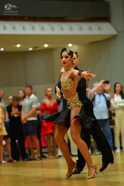 Dancesport competitor: Female dancer: black Latin dance dress with gold and bronze sequin and bead embe