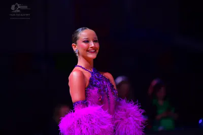 Dancesport competitor: Female dancer: purple latin dress with sequins, rhinestones, and large pink/mage