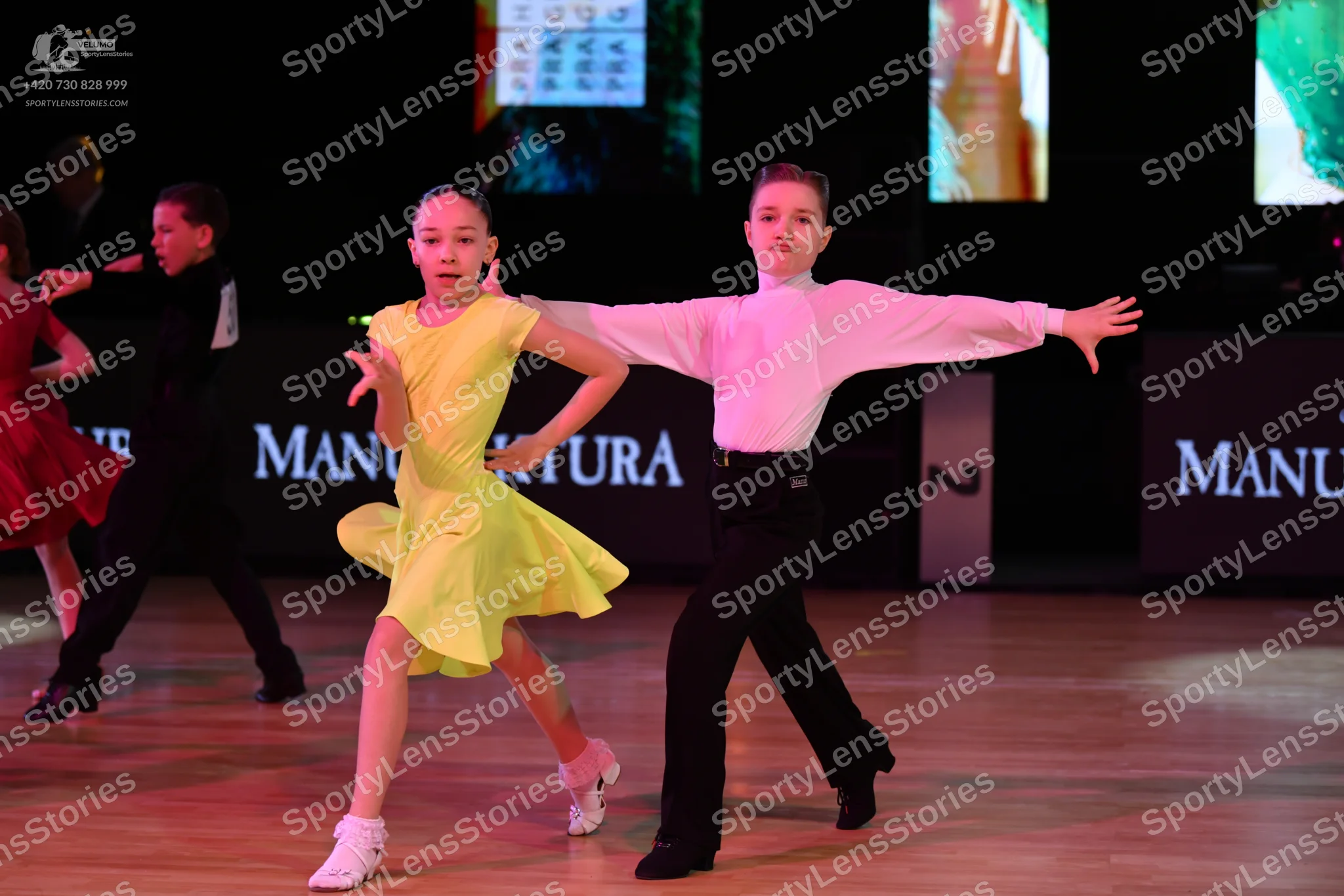 Dancesport competitor: Female dancer in foreground: yellow latin dress