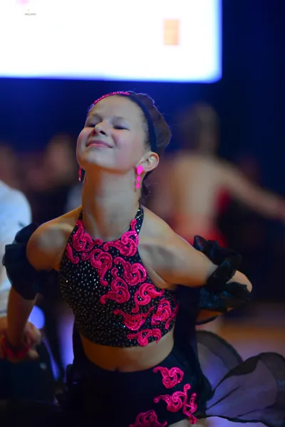 Dancesport competitor: Female dancer: black sequin halter top and skirt with bright pink swirl patterns