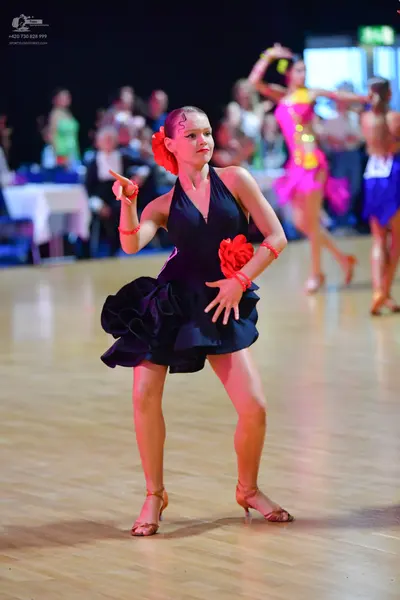 Dancesport competitor: Female dancer in foreground: black Latin dress with a halter neck and ruffled sk