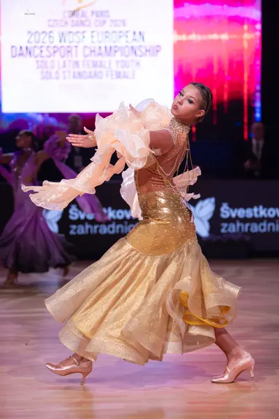 Dancesport competitor: Female dancer (foreground): gold, shimmering dance dress with a sequined bodice 