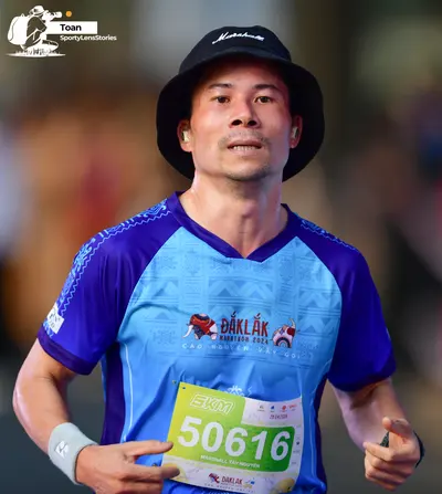 Marathon runner #50616: Runner 1: blue and purple patterned jersey, black bucket hat, white wristband