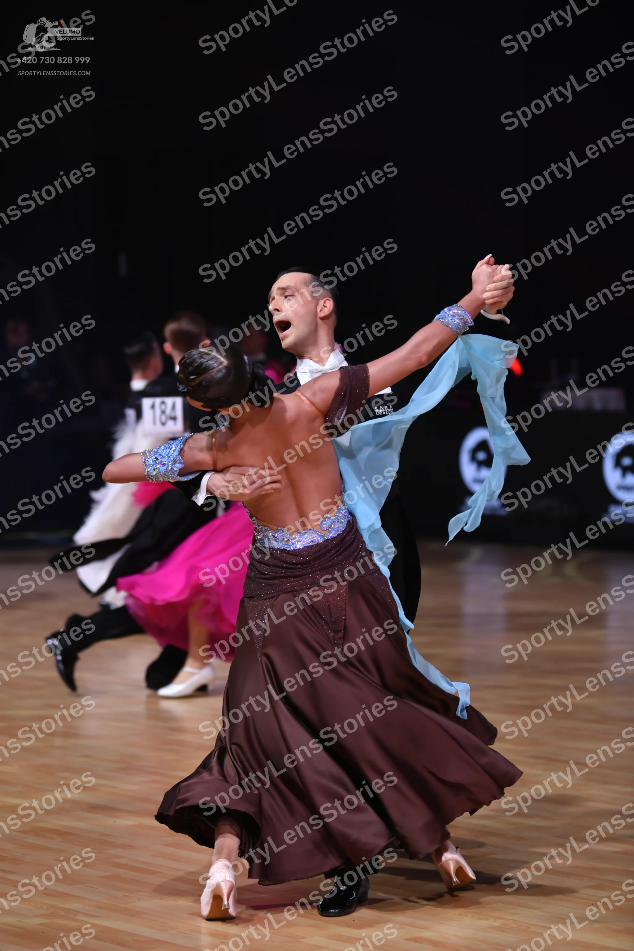 Dancesport competitor: Main female dancer: brown satin ballgown with a blue sequined and lace bodice, a