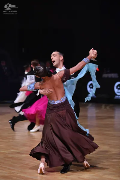 Dancesport competitor: Main female dancer: brown satin ballgown with a blue sequined and lace bodice, a