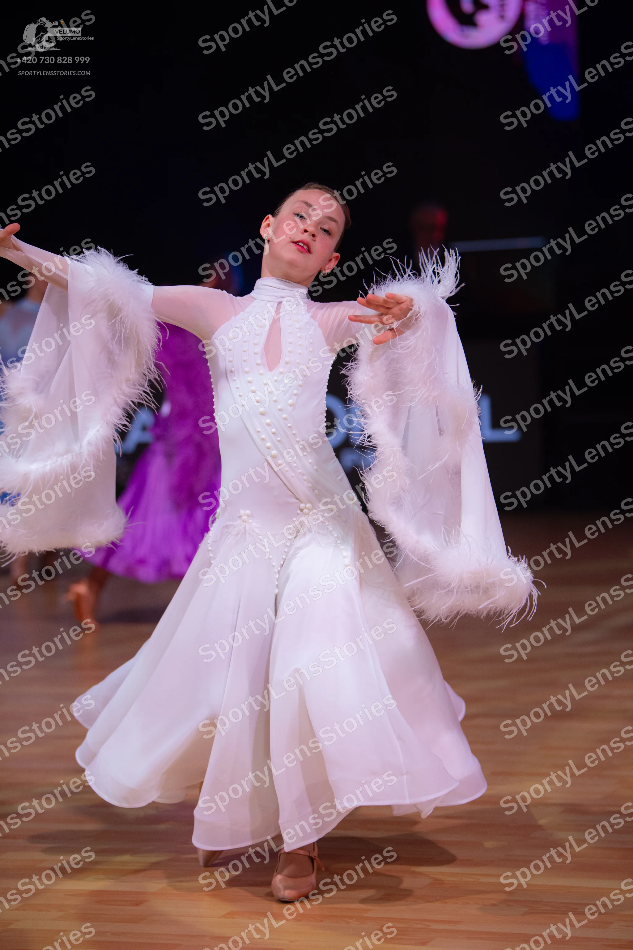 Dancesport competitor: Female dancer in foreground: white ballroom dress with a high neckline, keyhole