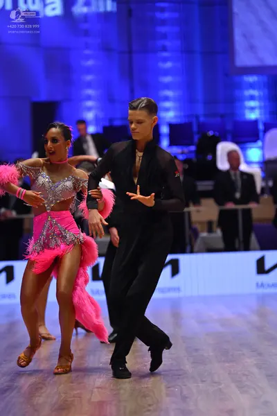 Dancesport competitor: Female dancer: pink Latin dress with silver sequins and long pink feather/fringe