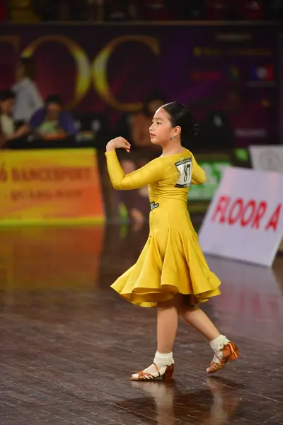 Dancesport competitor: Female dancer: yellow long-sleeved latin dress with a flared skirt and nude-colo