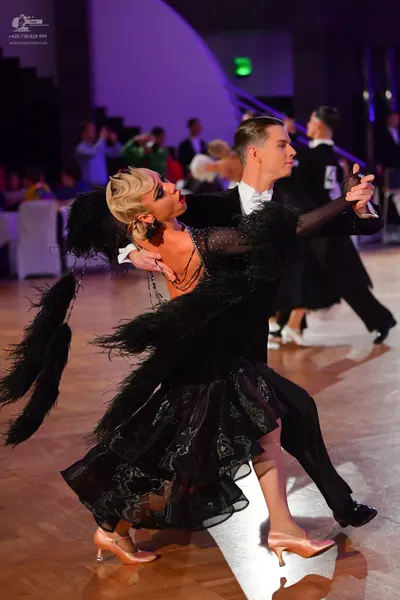 Dancesport competitor: Female dancer: black Latin dress with large black feathers, sheer fabric with si