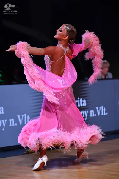 Dancesport competitor: Female dancer: pink Latin dress with sparkling stones/sequins, featuring large p