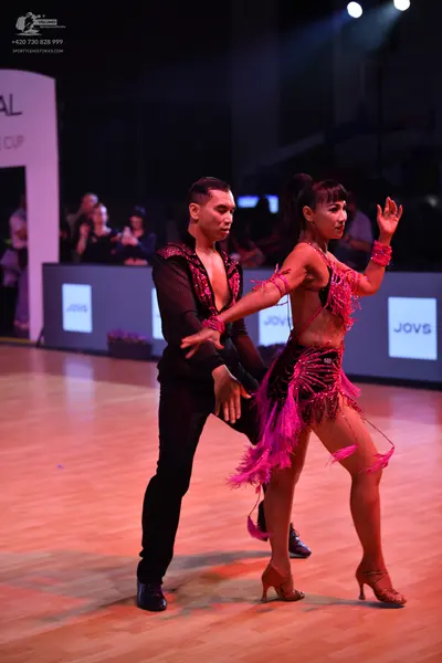 Dancesport competitor: Male dancer: black latin dance shirt with pink/red sequin embellishments and bla