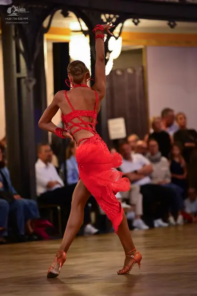 Dancesport competitor: Female dancer: red latin dress with sequins and an asymmetrical skirt, paired wi