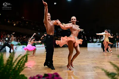 Dancesport competitor: Male dancer in foreground: peach-colored long-sleeve shirt with subtle texture a