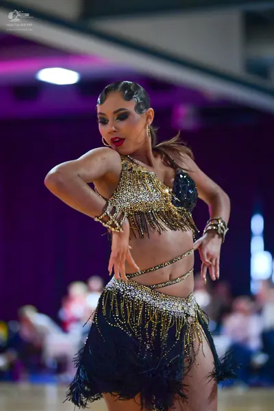 Dancesport competitor: Female dancer: gold and black latin dance costume featuring a sequined top with 
