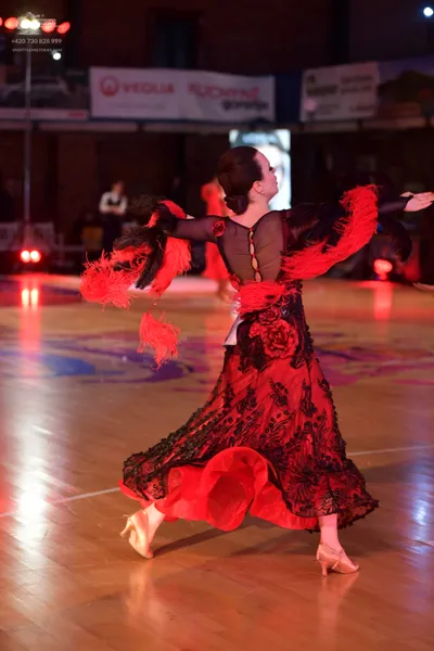 Dancesport competitor: Female dancer: red and black Latin dance dress featuring long black lace sleeves