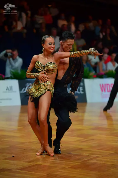 Dancesport competitor: Female dancer: gold sequined latin dance outfit with a two-piece style, featurin