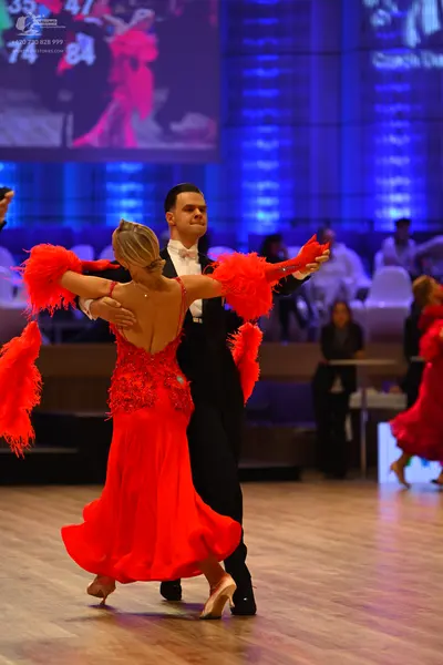 Dancesport competitor: Female dancer: red latin dress with feathered sleeves