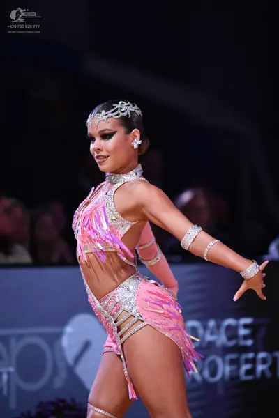 Dancesport competitor: Female dancer: pink latin costume with sequins, rhinestones, and pink fringe, in