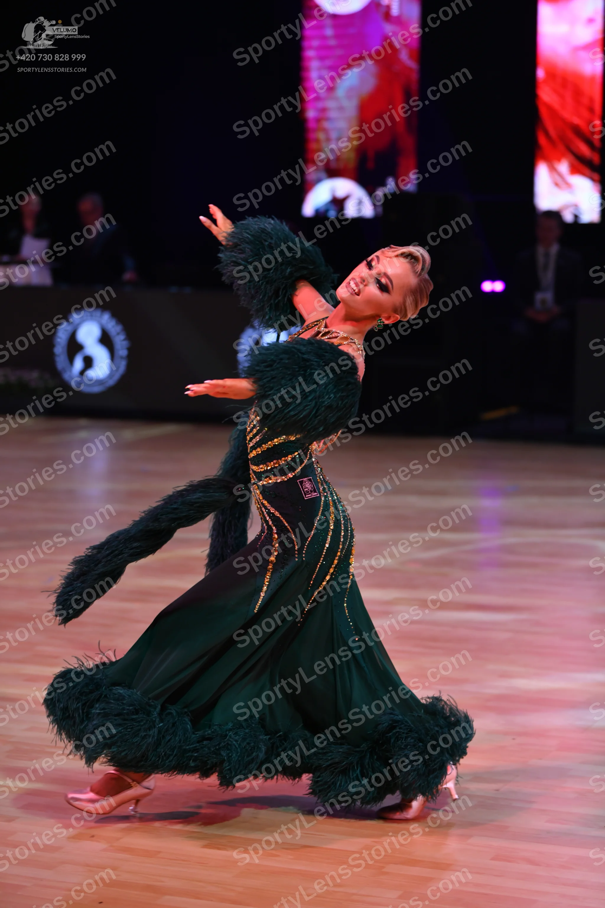 Dancesport competitor: Female dancer: dark green ballroom gown with gold sequin/beaded patterns and lar