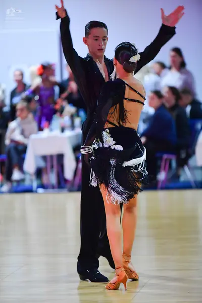 Dancesport competitor: Male dancer: black long-sleeved dance top with subtle embellishments at the neck
