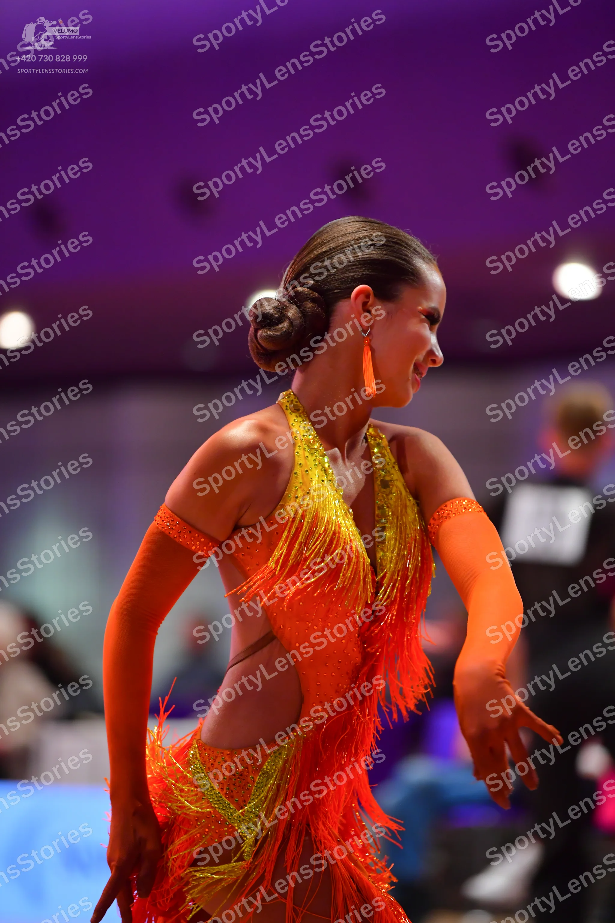 Dancesport competitor: Female dancer: bright orange and yellow sequined Latin dance dress with long fri