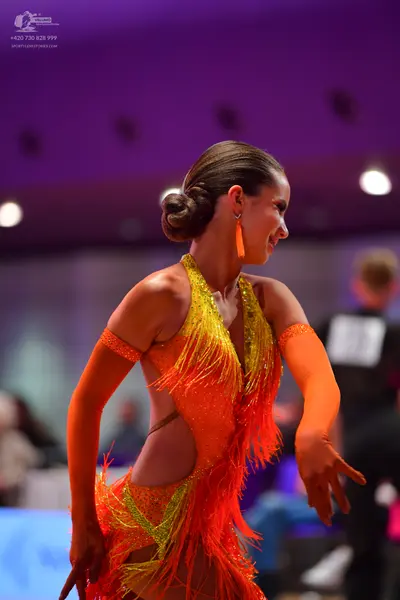 Dancesport competitor: Female dancer: bright orange and yellow sequined Latin dance dress with long fri