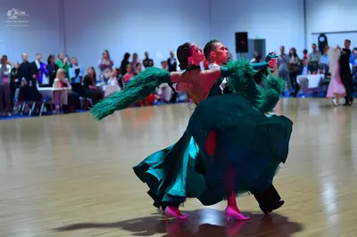 Dancesport competitor: Female dancer: Emerald green ballgown with a voluminous, flowing skirt and large