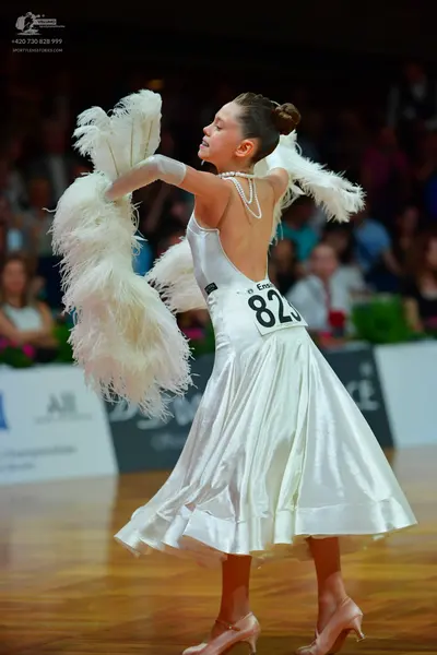 Dancesport competitor: Female dancer: white satin ballroom gown with large white feather-like accents