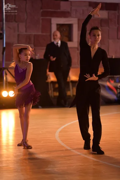 Dancesport competitor: Female dancer: purple Latin dress with fringe and tan-colored dance shoes