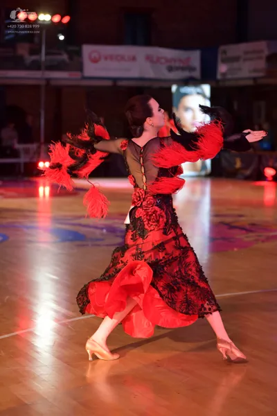 Dancesport competitor: Female dancer: red and black latin dress with black lace, red feathers on sleeve