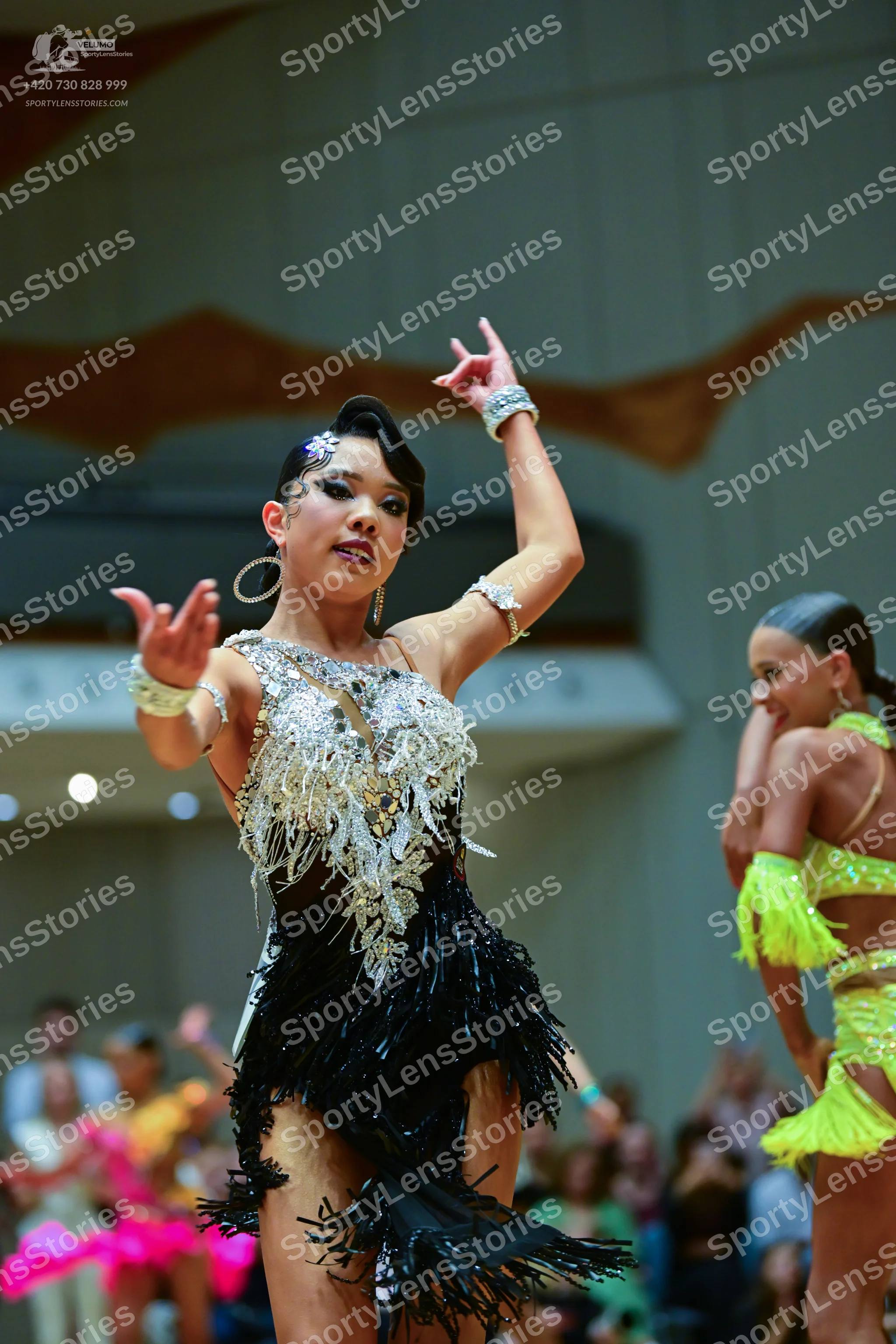 Dancesport competitor: Female dancer in foreground: black Latin dance dress with a heavily embellished