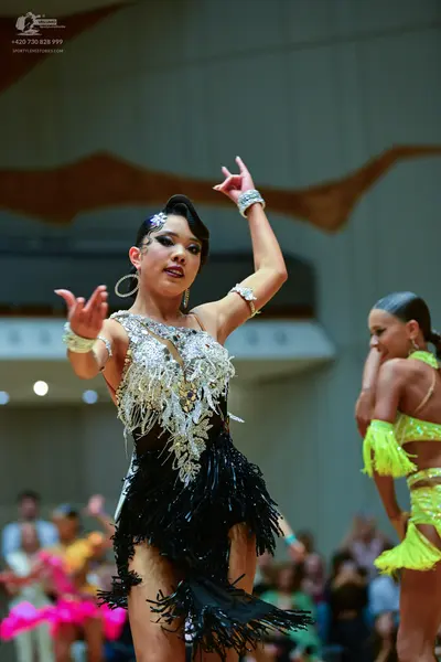 Dancesport competitor: Female dancer in foreground: black Latin dance dress with a heavily embellished 