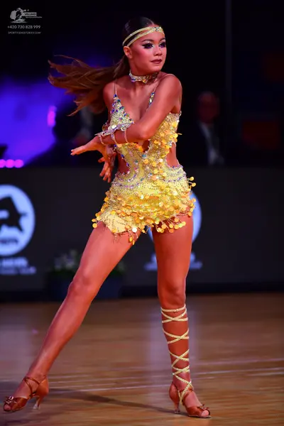 Dancesport competitor: Female dancer: bright yellow Latin dance costume heavily embellished with sequin