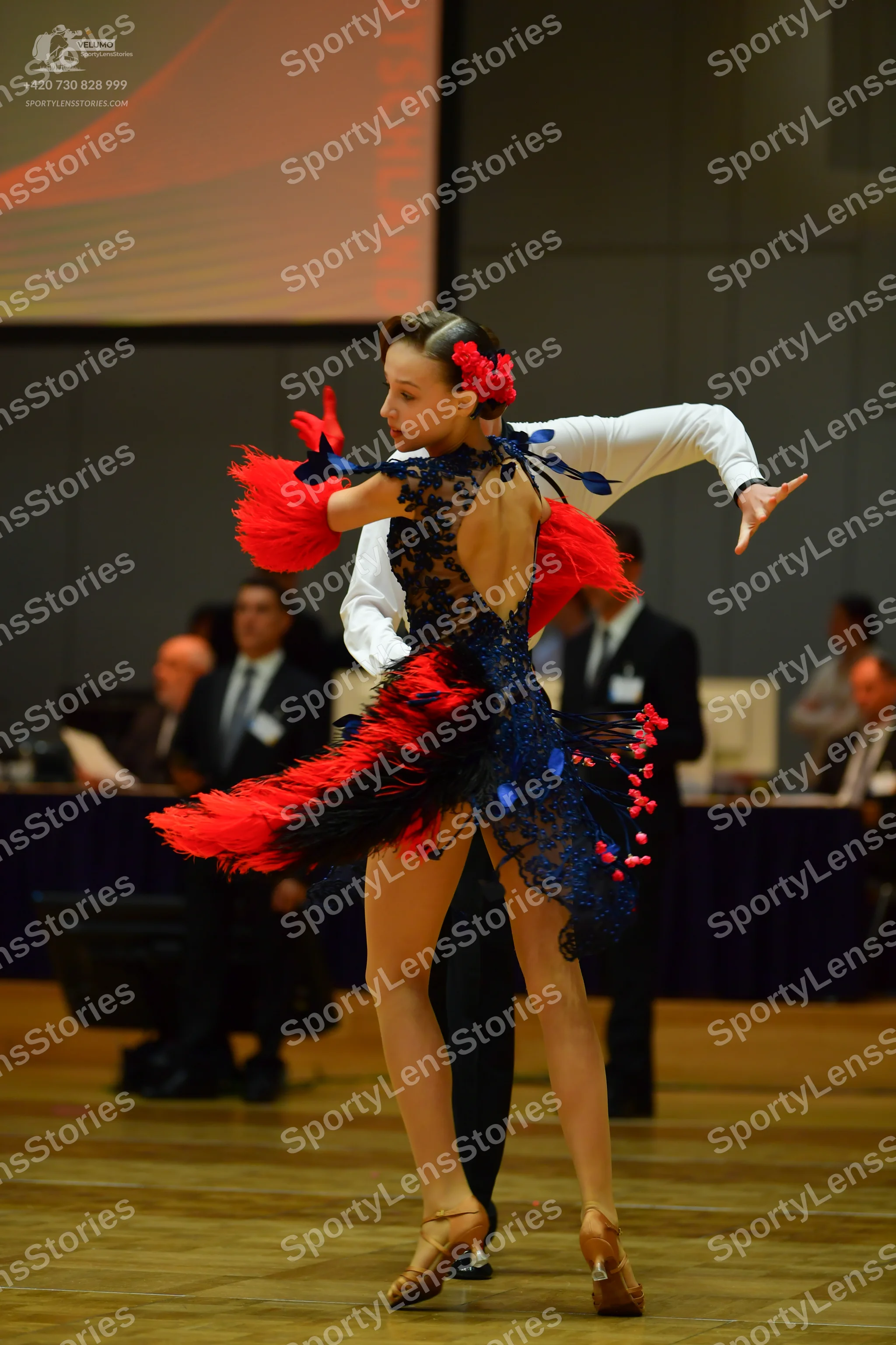 Dancesport competitor: Female dancer: navy blue and red Latin dance dress featuring red fringe/feathers