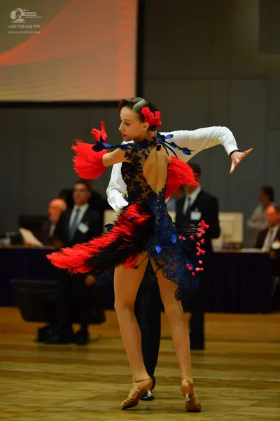 Dancesport competitor: Female dancer: navy blue and red Latin dance dress featuring red fringe/feathers