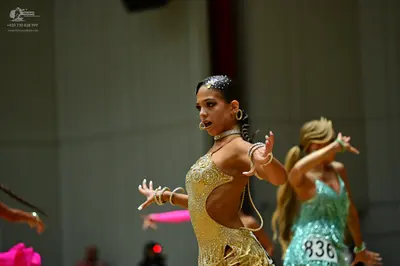 Dancesport competitor #836: Female dancer in foreground: gold sequined latin dress with cutouts and intricat