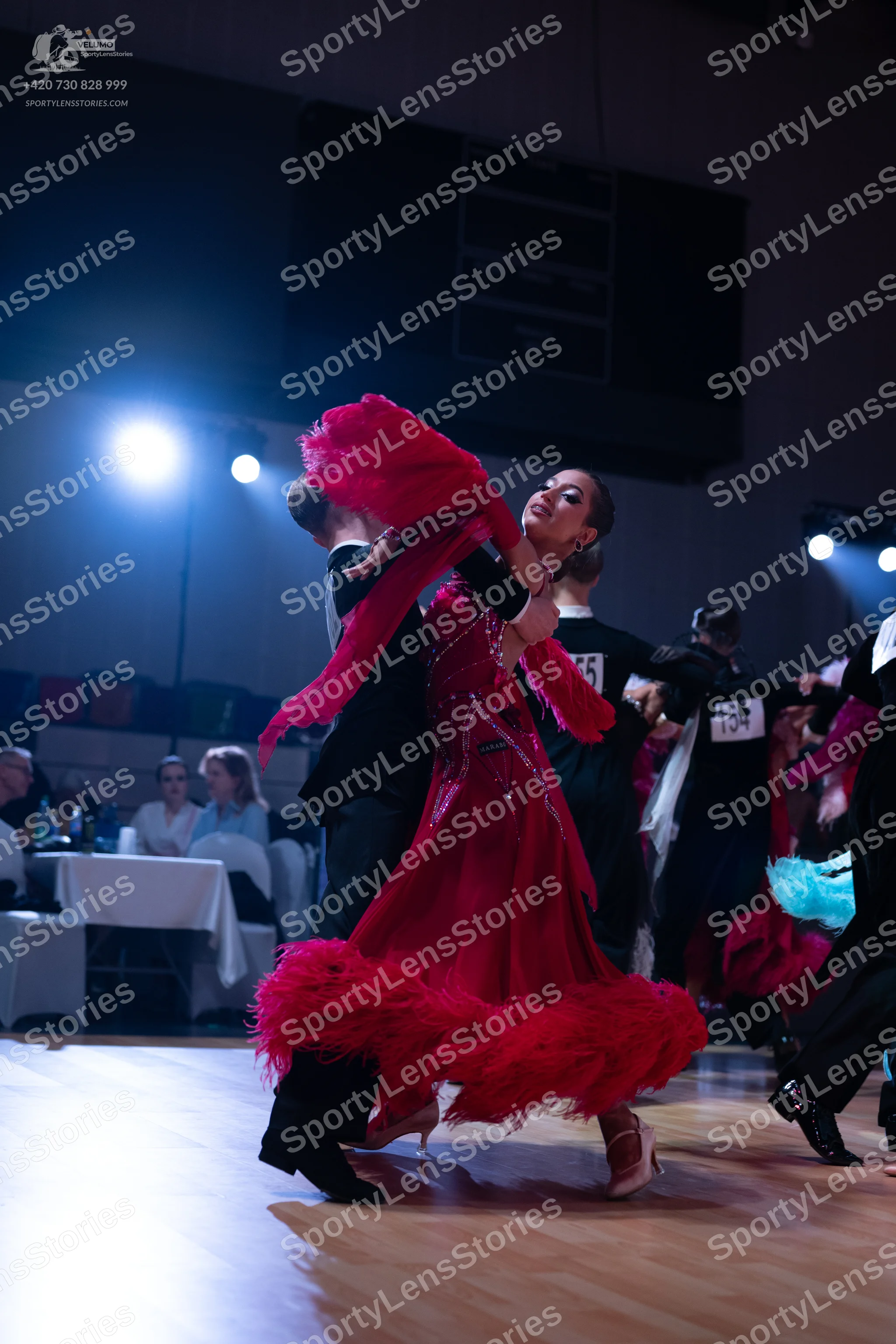 Dancesport competitor: Female dancer: dramatic red ballroom dress with voluminous red feather or fringe