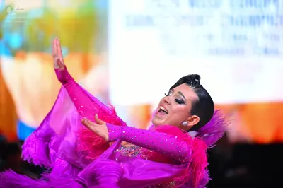 Dancesport competitor: Female dancer: bright pink Latin dance costume featuring sequins and large pink 