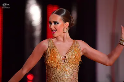 Dancesport competitor: Female dancer: gold Latin dance costume featuring a sequined bodice with long go