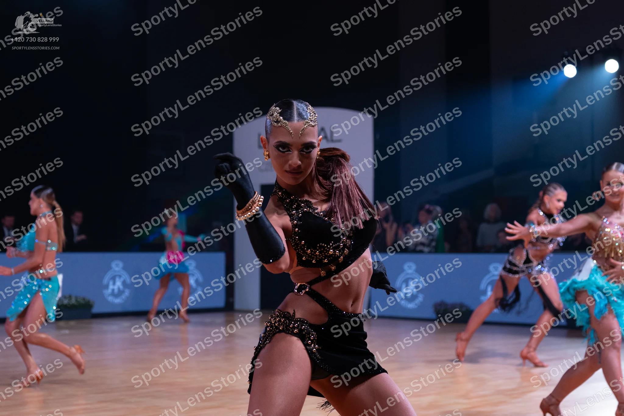 Dancesport competitor: Female dancer (center): black Latin dance costume with heavy sequin and crystal