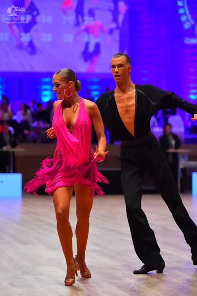 Dancesport competitor: Female dancer: bright pink latin dress with sequins on the bodice and fringe at 