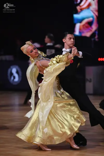Dancesport competitor: Male dancer: black formal suit with a white shirt, black bow tie, and a small re