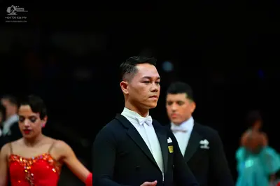 Dancesport competitor: Male dancer in foreground: black suit with white shirt and white bowtie