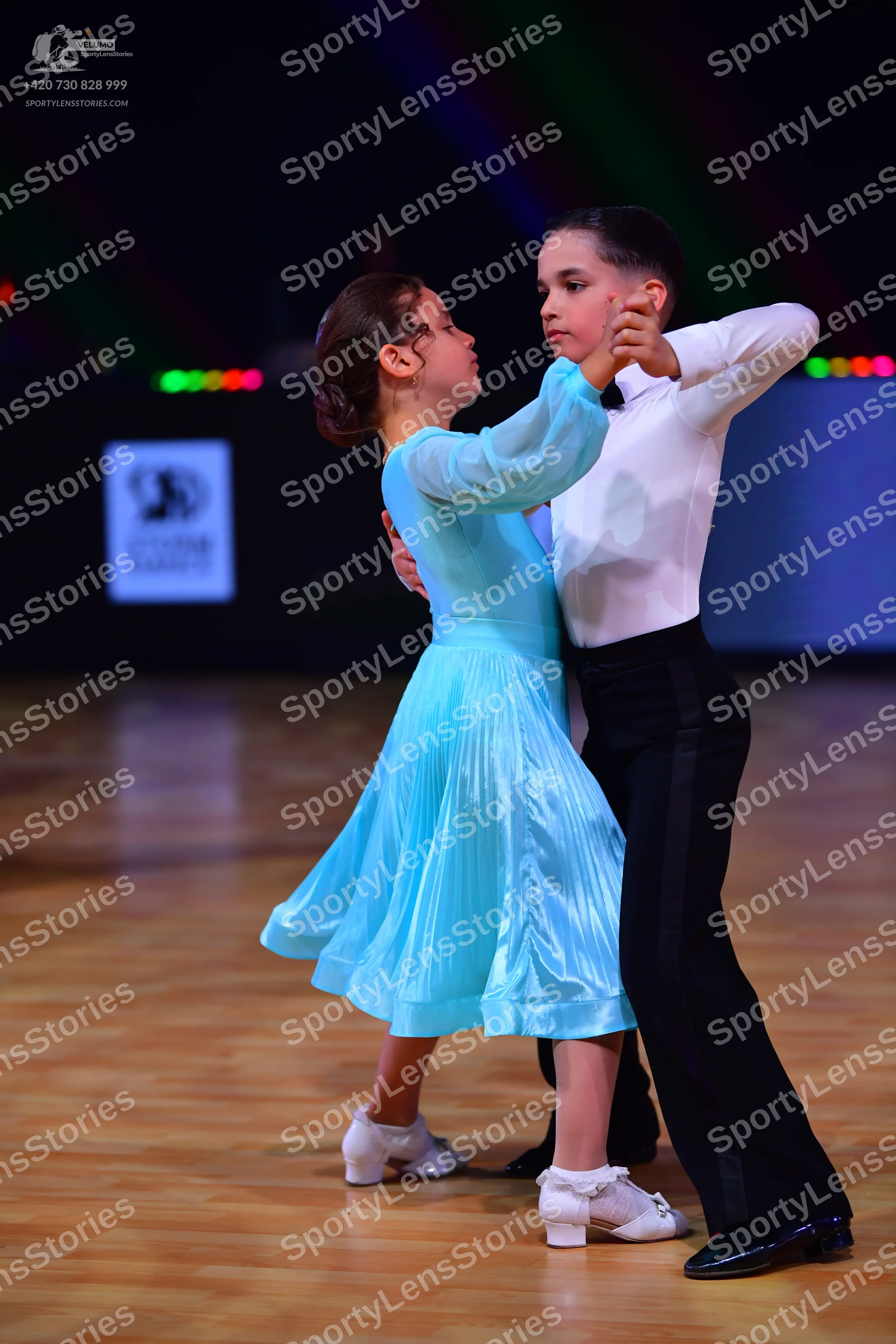 Dancesport competitor: Female dancer: light blue satin-like dress with long sleeves and a flared skirt