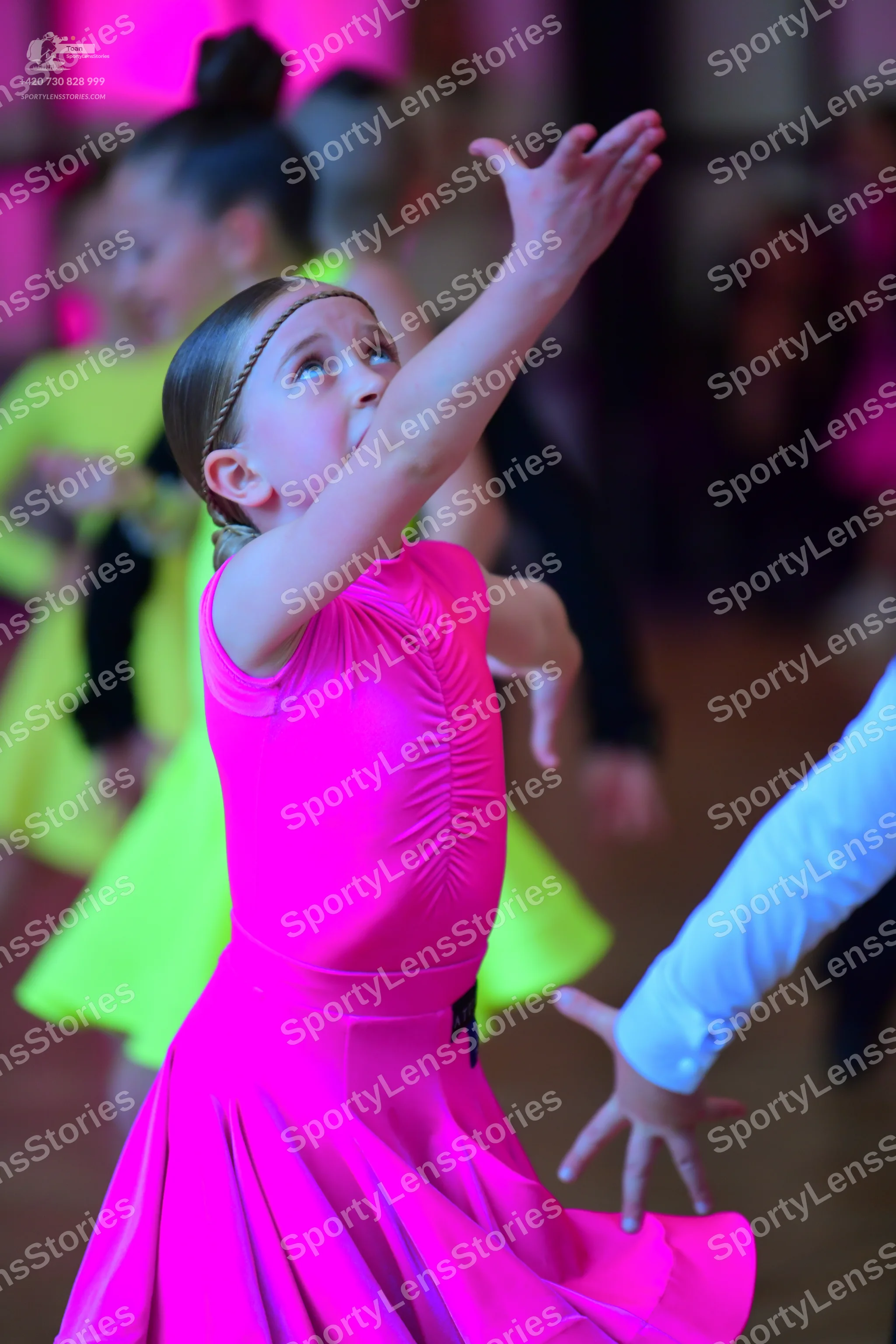 Dancesport competitor: Female dancer in foreground: bright pink sleeveless dress with a full, flowing s