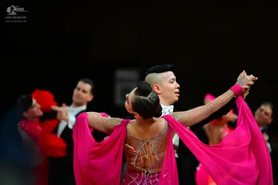 Dancesport competitor: Female dancer in foreground: magenta latin dress with a sheer mesh back featurin