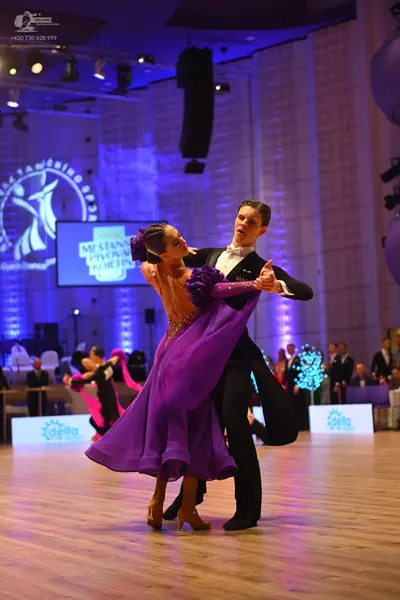 Dancesport competitor: Female dancer: purple flowing dance dress with dark purple ruffled embellishment