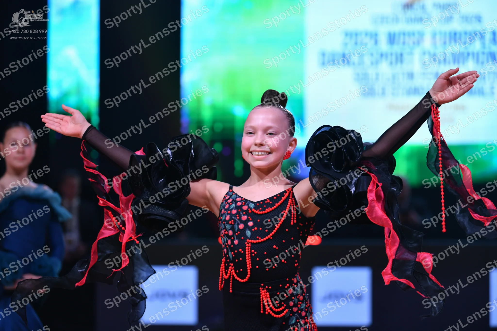 Dancesport competitor: Female dancer (center): black latin dance costume with pink and red sequin patte
