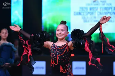Dancesport competitor: Female dancer (center): black latin dance costume with pink and red sequin patte