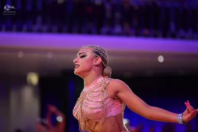 Dancesport competitor: Female dancer: light pink sequined Latin dance costume with draped beaded or cha
